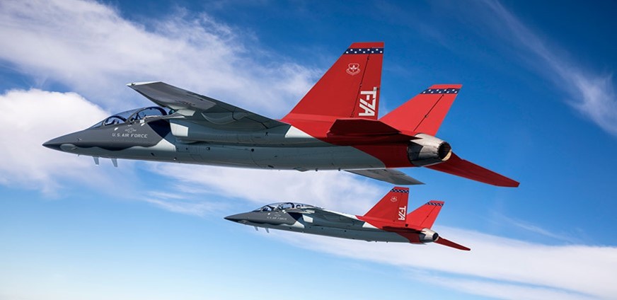Two red and white T-7A Red Hawk jets flying above the clouds